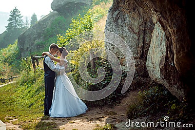 Romantic outdoor wedding portrait. Stylish newlyweds are hugging and standing head-to-head to each other on the sunny Stock Photo