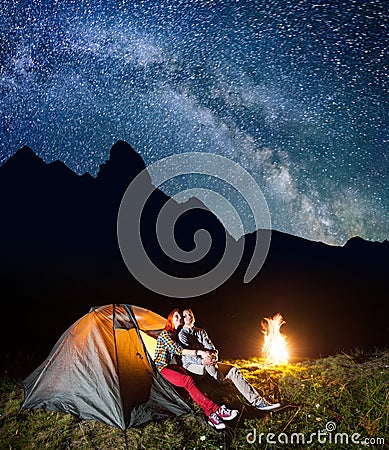 Romantic pair lovers looking to the shines starry sky and Milky way in the camping at night near campfire Stock Photo