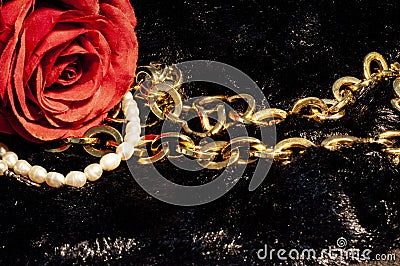 Romantic scene with a red rose, golden necklace and pearls. Stock Photo