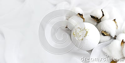 Romantic spa concept with bath bomb, cotton flowers on waved silk background. Luxury cosmetics branding. Stock Photo