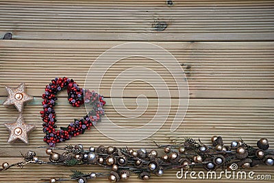 Christmas photography with silver and gold colored acorn tree ornament on natural rustic wood background with red berry love heart Stock Photo