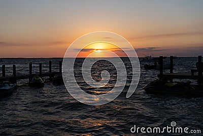 romantic sundown seascape with silhouette pier jet ski and yacht boats, summer vacation. Stock Photo
