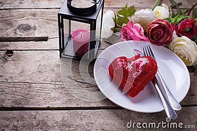 Romantic table setting. Decorative red heart, knife and fork on white plate Stock Photo