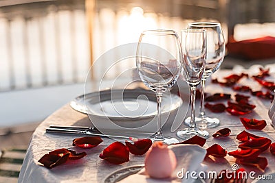 Romantic Valentine`s Day dinner setup with rose petals Stock Photo