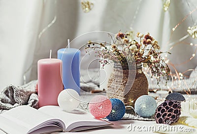 Romantic winter and New Year`s style interior view with a candle, book, garland and dryed flowers in rustic vase Stock Photo