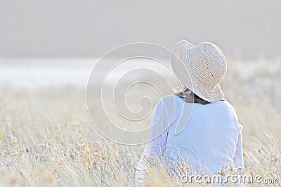 Romantic woman sitting in tall long grass Stock Photo