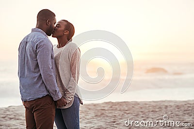 Romantic young African couple kissing on a beach at sunset Stock Photo