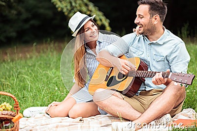 Romantic young couple having a great time on a picnic, playing guitar and singing Stock Photo