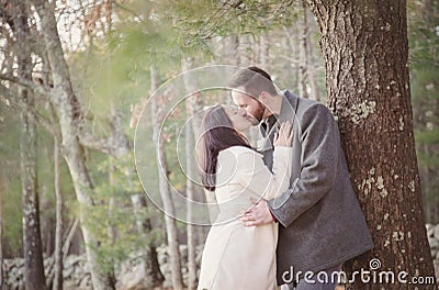 Romantic young couple kissing under a tree on a cold fall day Stock Photo