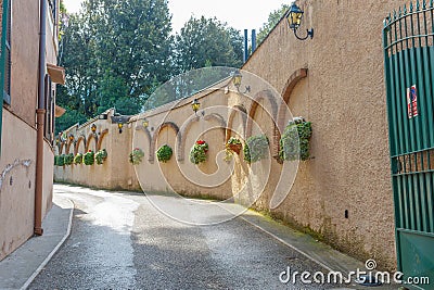 Narrow curving lane with potted plants on wall Stock Photo