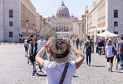 ROME, ITALY - APRIL 27, 2019: Young woman photographs the Saint Peter`s Basilica, Rome, Italy. Editorial Stock Photo