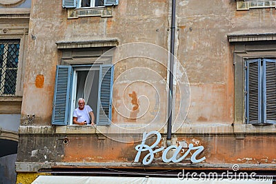 Italian pensioner looking outside from the window. Very old building in Rome, capital of Italy, sign for Bar cafe downstairs Editorial Stock Photo
