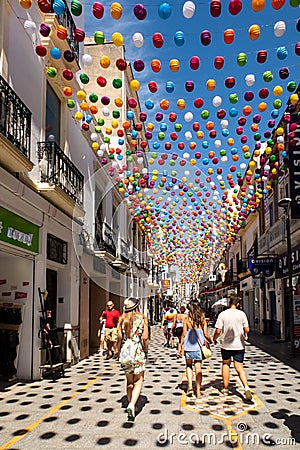 RONDA, Spain, 02/09/19. Calle La Ronda picturesque narrow street with colorful balls decorations hanging, bars, shops,people. Editorial Stock Photo