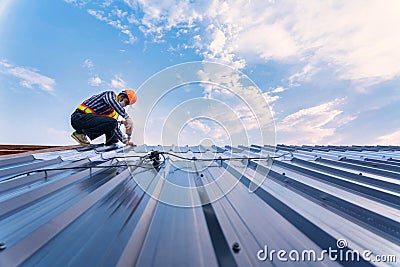 Roof construction concept, Roofer using air or pneumatic nail gun and installing on new roof metal sheet Stock Photo