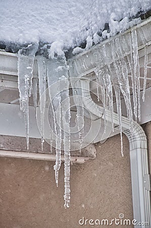 Roof line with long icicles taken while it is still snowing Stock Photo