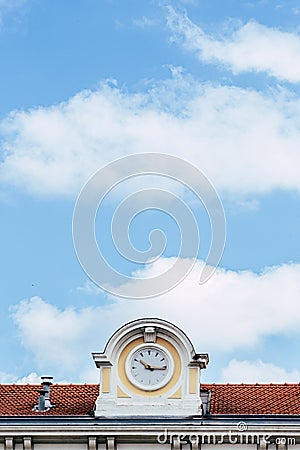 Roof of an old train station with a beautiful clock and a summer sky Stock Photo