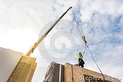 Roofer builder worker with crane installing structural Insulated Panels SIP. Building new frame energy-efficient house. Stock Photo