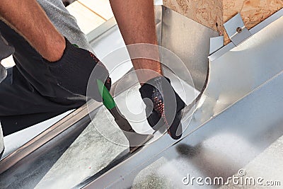 Roofer builder worker finishing folding a metal sheet using special pliers with a large flat grip. Stock Photo