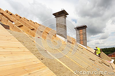 Roofer builder worker installing roof insulation material rockwool on new house under construction. Stock Photo