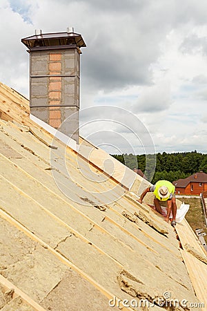 Roofer builder worker installing roof insulation material rockwool on new house under construction. Stock Photo