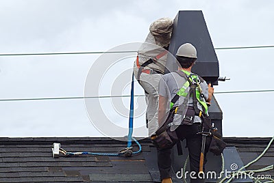 Roof repair construction worker roofer man roofing security rope Editorial Stock Photo