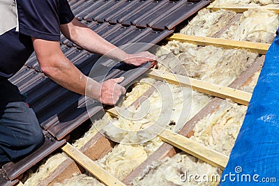 A roofer laying tile on the roof Stock Photo