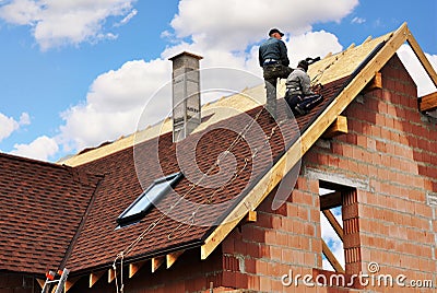 Roofers lay and install asphalt shingles. Roof repair with two roofers. Roofing construction with roof tiles, asphalt shingles. Editorial Stock Photo