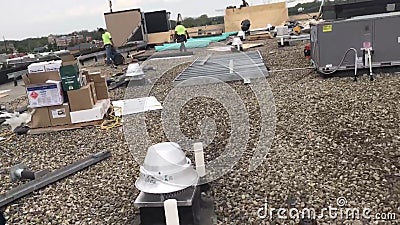 Roofers repairing areas of a commercial flat roof and materials, tools and supplies Editorial Stock Photo