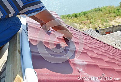 Roofing construction. Roofer installing metal roof sheets on the Stock Photo