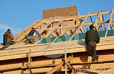 Roofing contractors installing house wooden beams framework with damp, vapor, waterproof membrane Roofing Construction Editorial Stock Photo