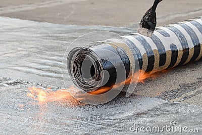 Roofing installation felt with heating and melting bitumen roll by torch on flame, closeup detail shoot Stock Photo