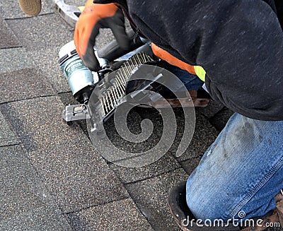 ROOFING WORK: professional roofer repairs shingles. Stock Photo