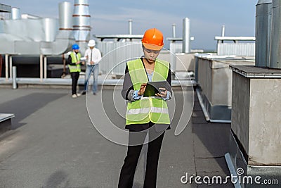 On the rooftop of construction site beautiful African engineer make a conversation with some worker using the tablet. Stock Photo