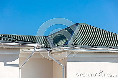 Rooftop of house with metal rain gutter system against blue sky Stock Photo