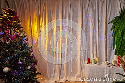 A room with a Christmas tree, a table and a curtain decorated for Christmas and New Year. A place for photo shoots in Stock Photo