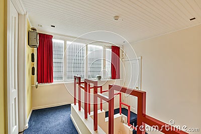 a room with red and white stairs and a window Stock Photo