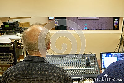 Room sound engineer at the concert. View of the stage from the technical room in the music hall. Soundman at a concert of singers Editorial Stock Photo