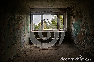 A room with a window and chairs in an old abandoned house. Dirty shabby walls. Stock Photo