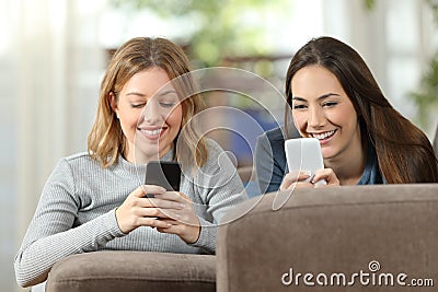 Roommates using two smart phones at home Stock Photo