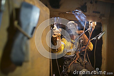 Rope access welder commencing welding in confined space Stock Photo