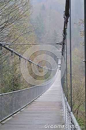 Rope bridge in misty mountains Stock Photo