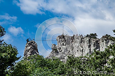 Rope ladder over abyss leading to catholic cross standing on top of mountain, Crimea Stock Photo