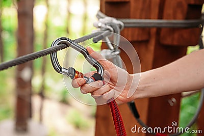 Rope park. The hand hooks the carabiners to the belay line. Close-up. Stock Photo