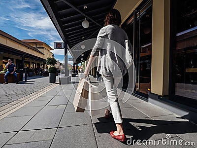 Rear view of single woman walking on the alley with multiple stores at the Editorial Stock Photo