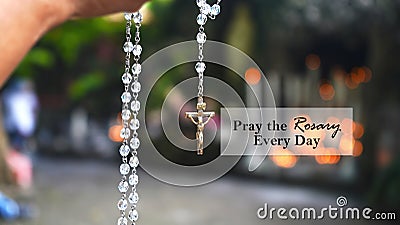 Rosary quote - Pray The Rosary every day. Praying rosary concept with person holding rosary beads in hand. Stock Photo