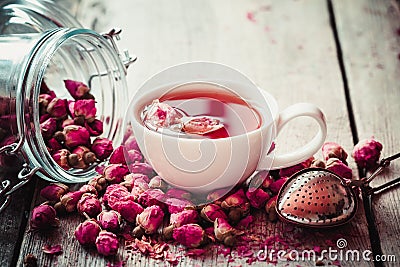 Rose buds tea, tea cup, strainer and glass jar with rosebuds Stock Photo