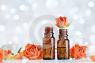 Rose essential oil bottles on white table with bokeh effect. Spa, aromatherapy, wellness, beauty background. Stock Photo