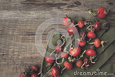 Rose hip berries, sweet briar fruits, gloves on wooden board Stock Photo