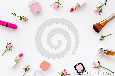 Rose, pink decorative cosmetics frame. Lipstick, bulk, eyeshadow and small rose flowers on white background top view Stock Photo