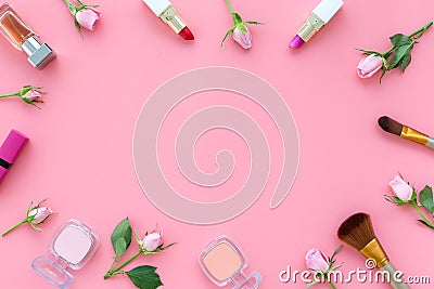 Rose, pink decorative cosmetics frame. Lipstick, bulk, eyeshadow and small rose flowers on pink background top view copy Stock Photo